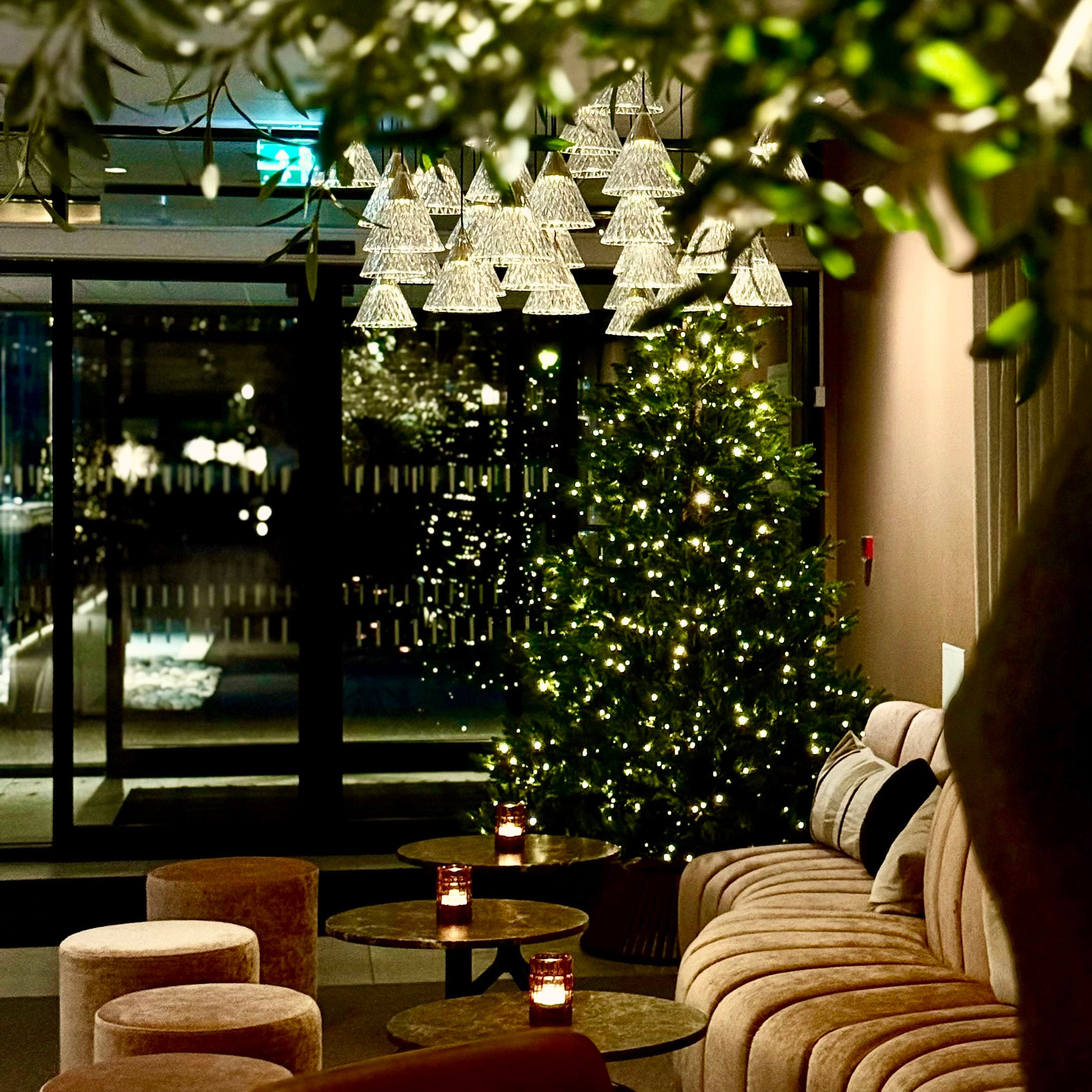 Elegant juledekorasjon med lysekrone og juletre i en moderne stue med koselig atmosfære.