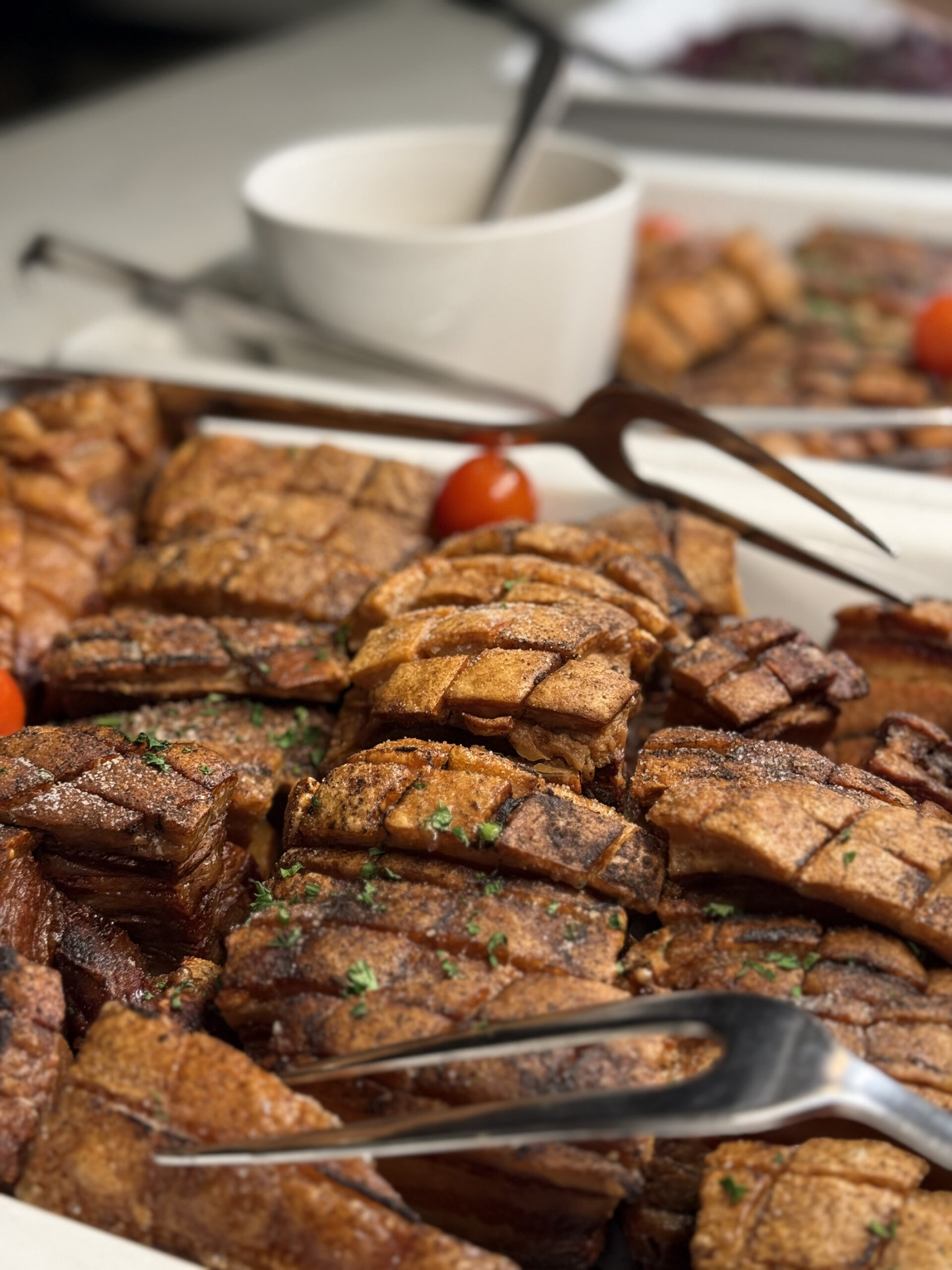 Delikat ribbe med sprø svor, servert med cherrytomater og tilbehør på en festlig buffet.